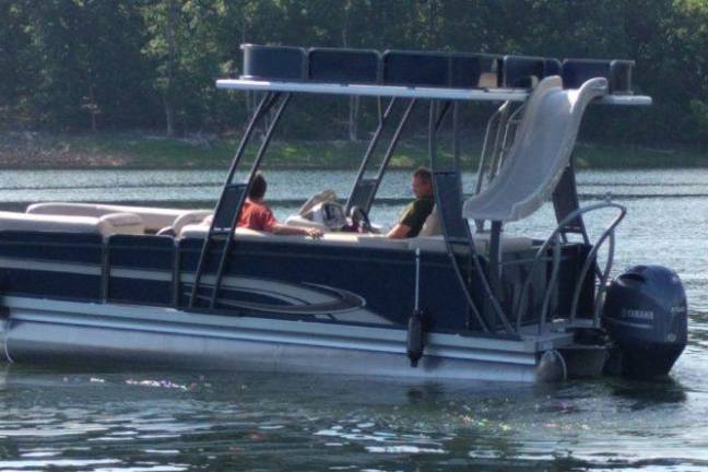 a man driving a 23' tritoon on a lake